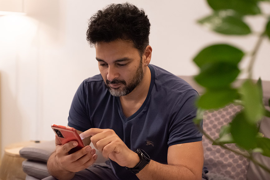 Family manager Rahman on the couch using his smartphone
