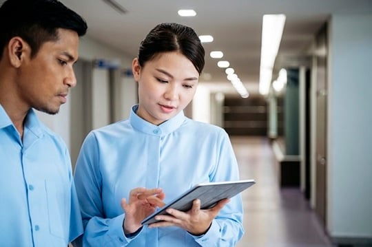 A female and male nurse working with a tablet.