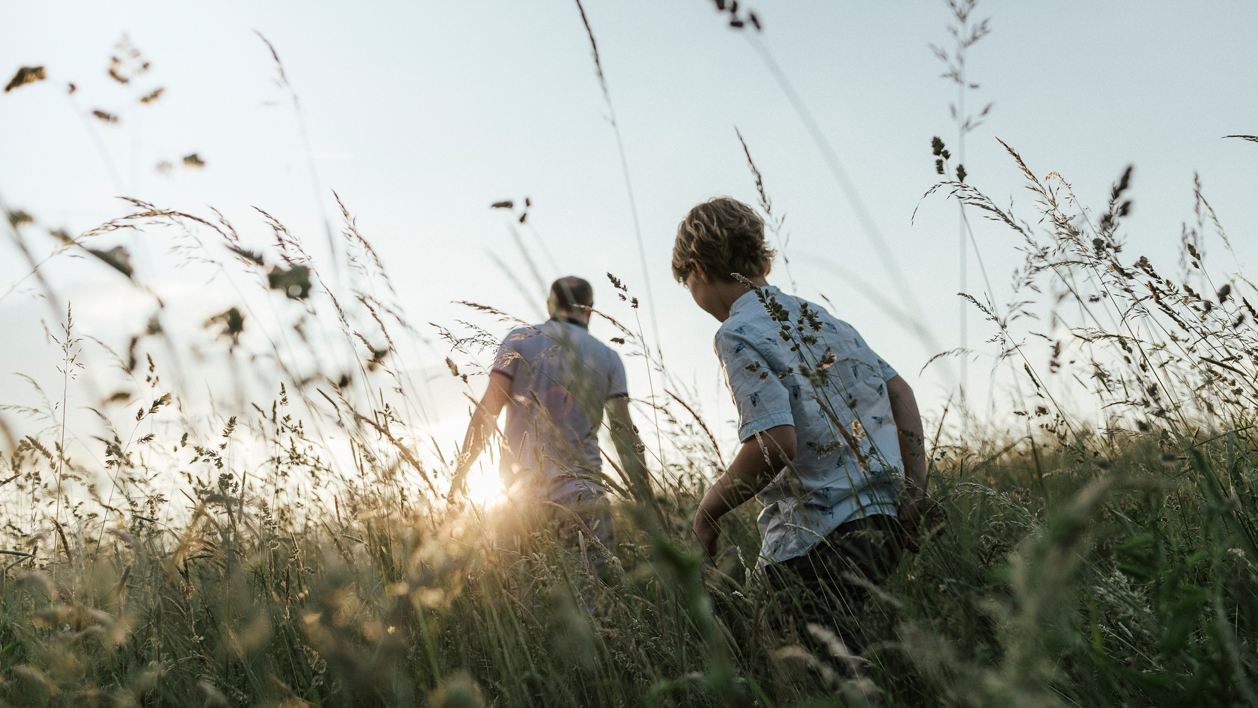 Father and son walking across a field at dusk