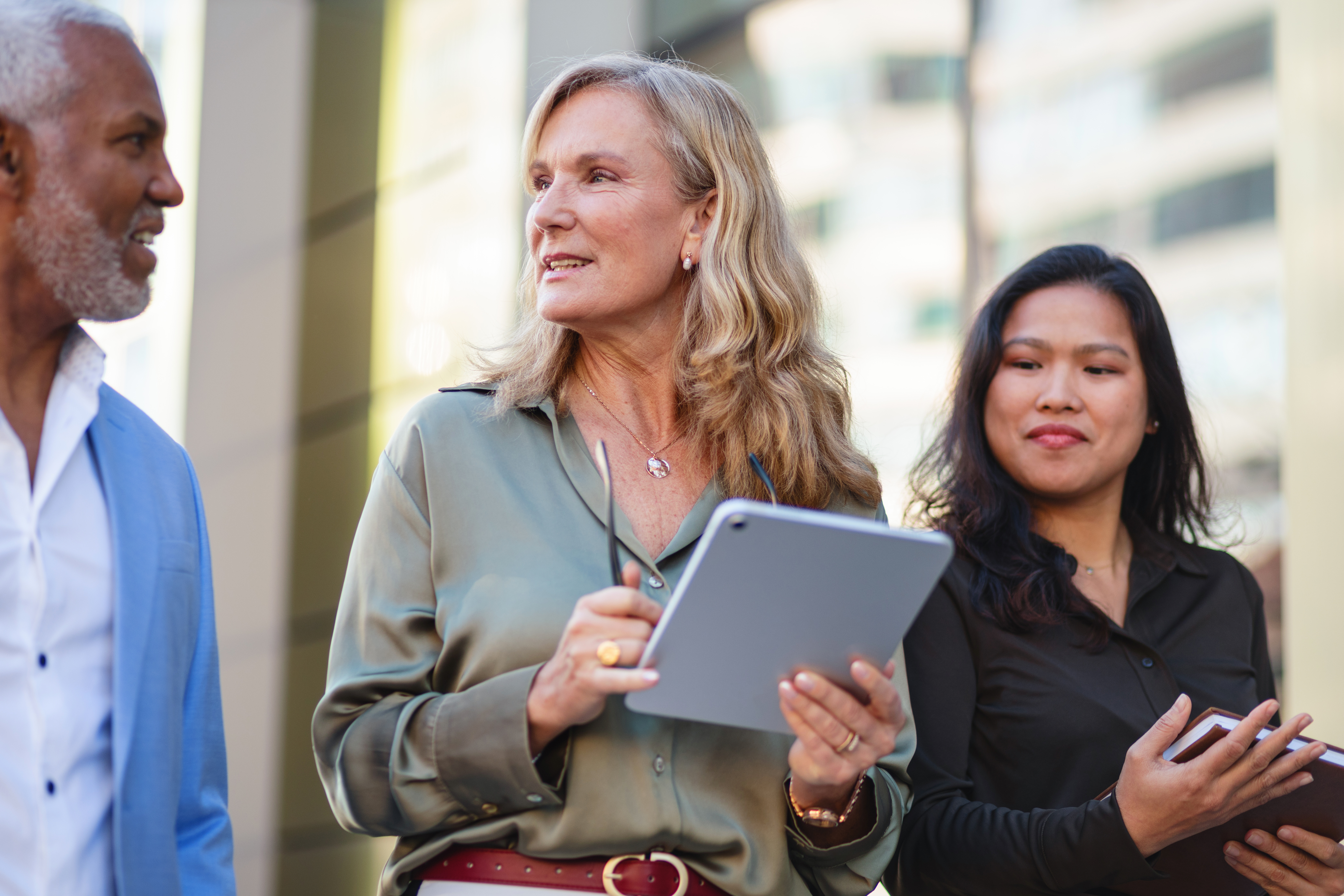 A multicultural group of business professionals engaged in conversation outdoors.